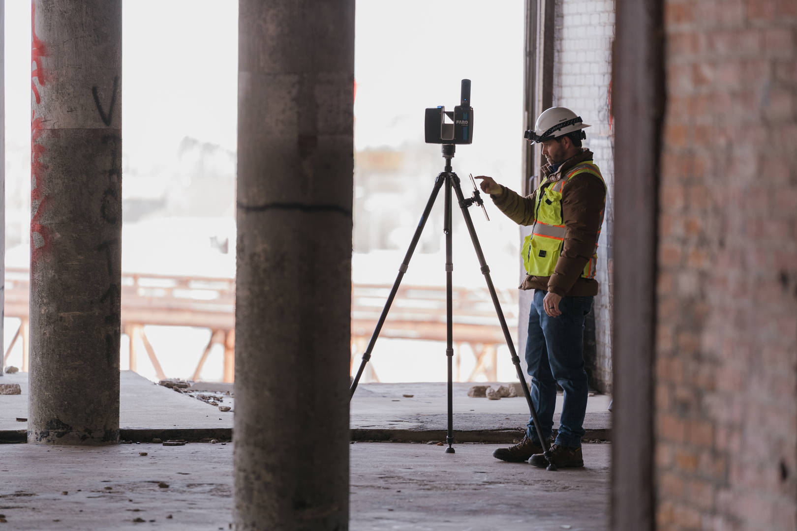 Man wearing personal protection equipment inside a derelict building, terrestrial laser scanning with a FARO Focus on a tripod