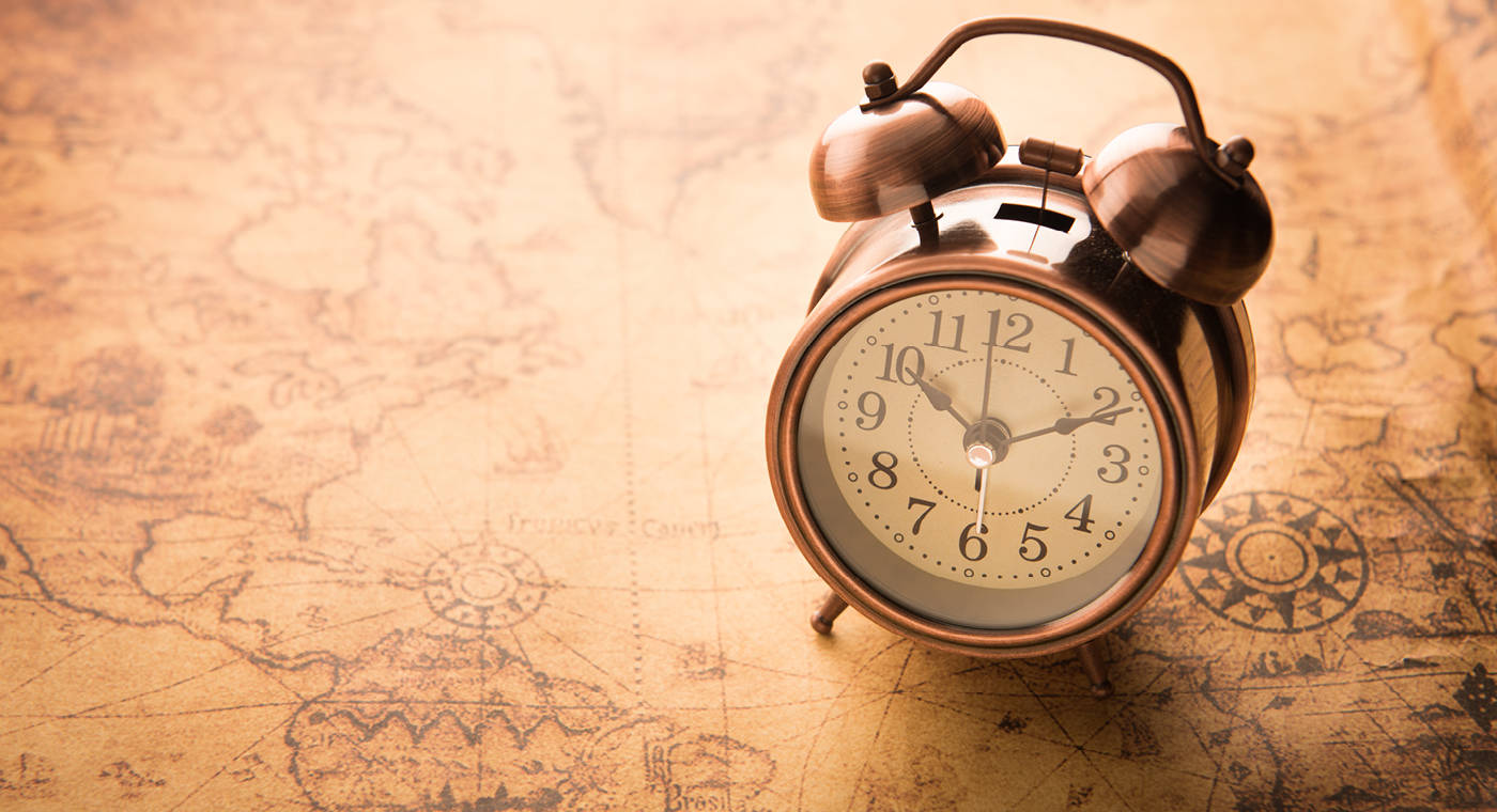 Alarm clock placed on top of an old map of the world